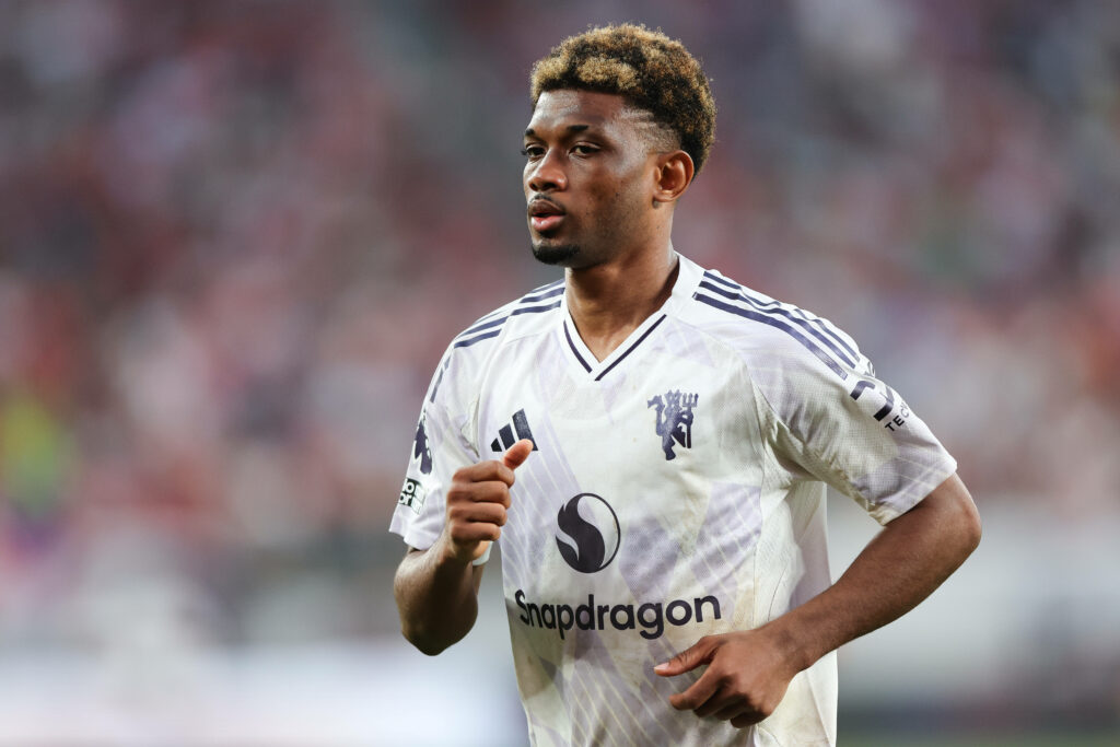 Amad Diallo jogs while wearing the Man United away kit.
